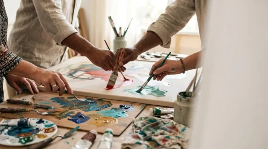 Diverse hands collaboratively creating art together in a communal workshop space