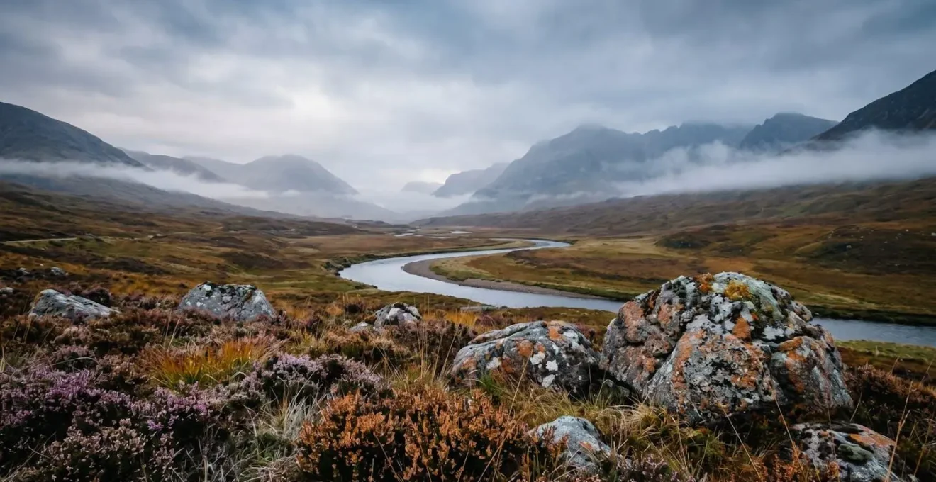 Dramatic Scottish Highland valley shrouded in autumn mist with rugged mountain peaks under moody overcast sky