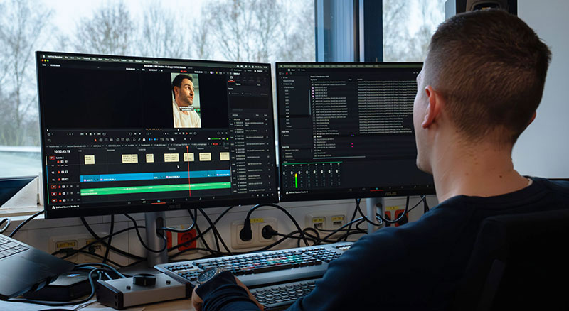 Contemporary collaborative workspace with multiple monitors displaying video editing interfaces in bright office interior