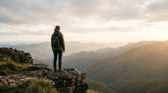 A traveler standing at a scenic overlook, gazing at a vast landscape with mountains and sky, symbolizing transformative travel experiences